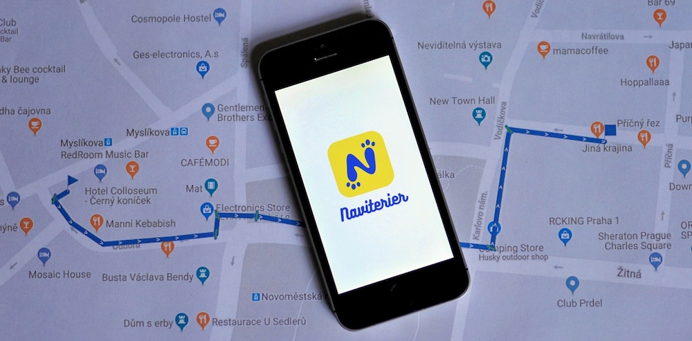 Mobilní telefon se zapnutým Naviterierem leží na mapě s nakreslenou pěšší trasou